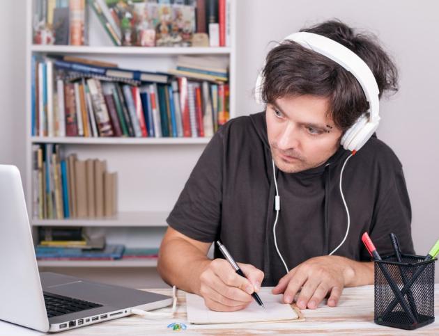 E-Learning. Man with headphones sydying by Laptop